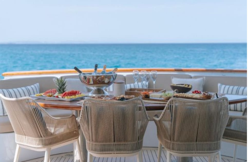 The aft deck table laid with fruit and champagne, open sea beyond