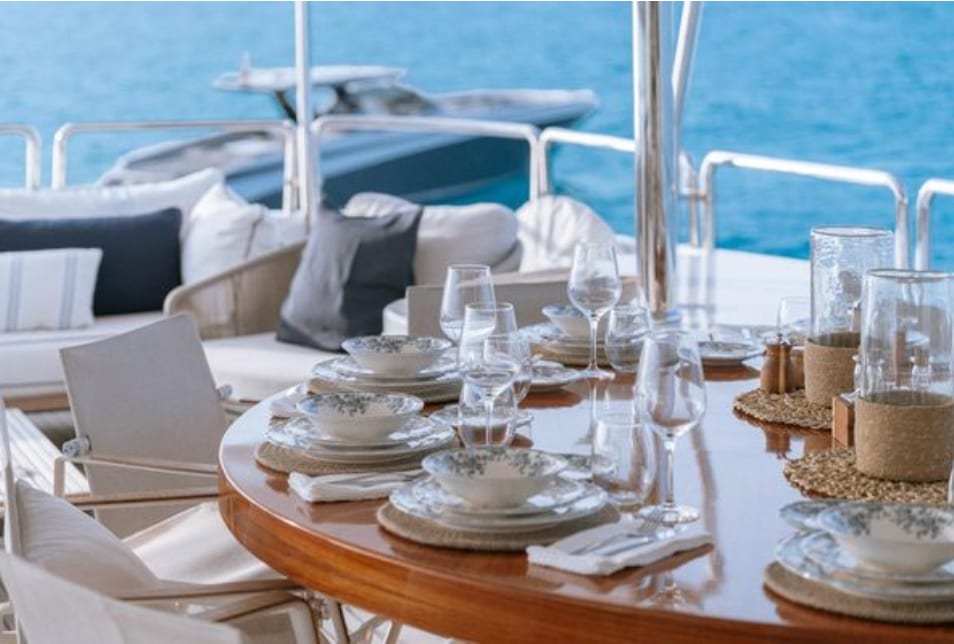 A round table laid for lunch on deck, the tender astern