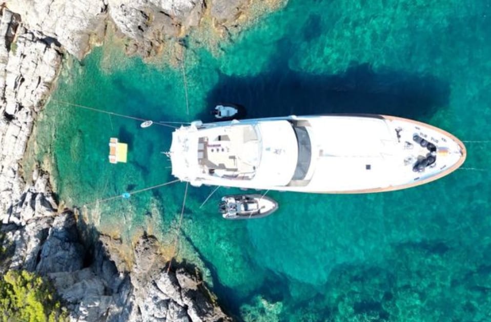 M/Y Friendship from directly overhead, anchored in a Balearic cala