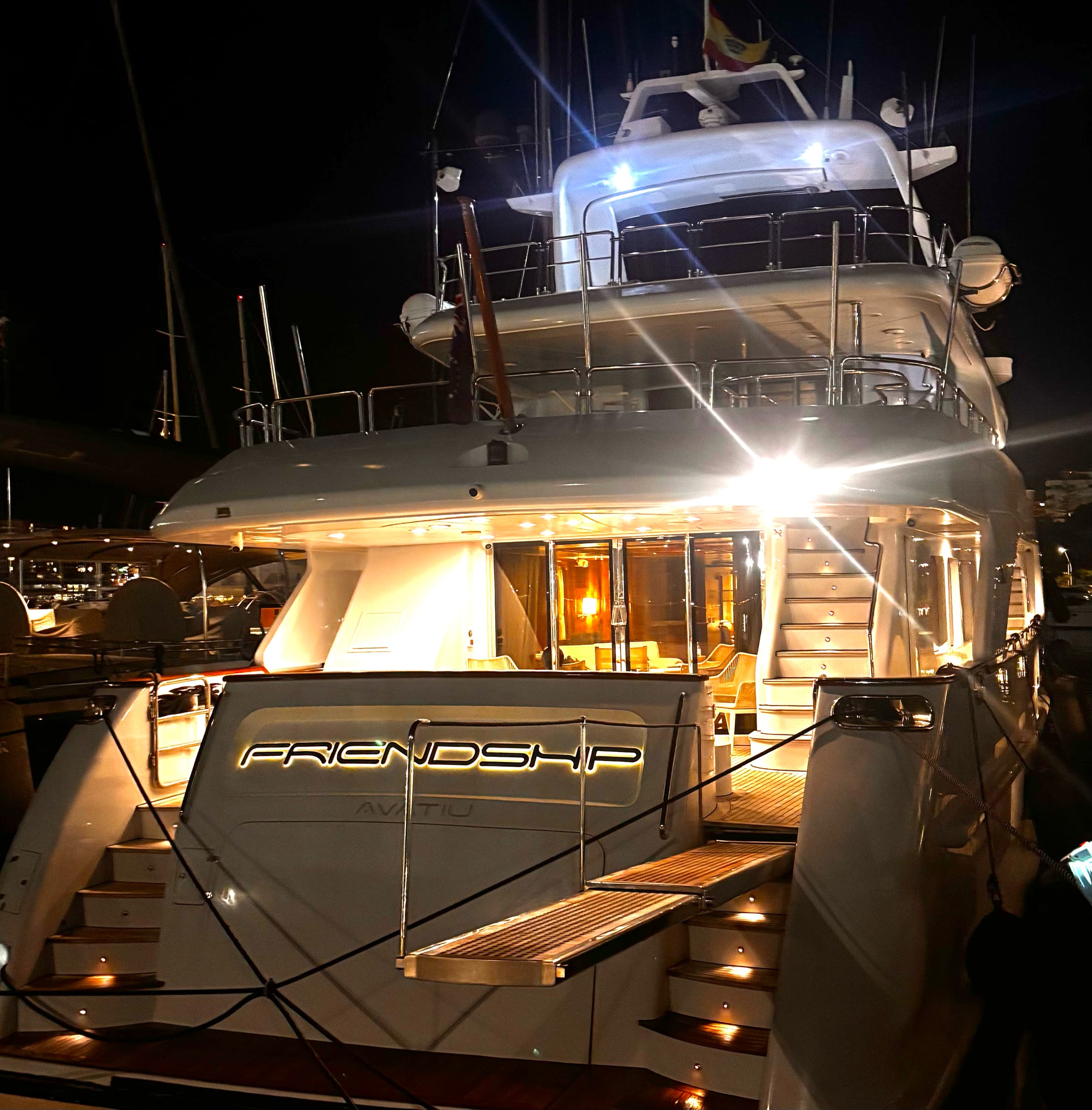 M/Y Friendship lit alongside at night, her name on the transom